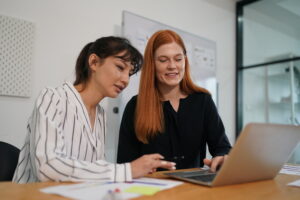 Two women collaborating in an office, discussing the evolving RAC Audit landscape.